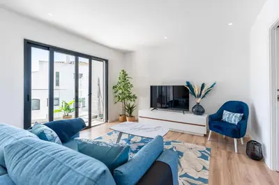a living room with a blue couch and a tv at Stunning 3 BDR Flat W/ Rooftop Pool by LovelyStay in Albufeira