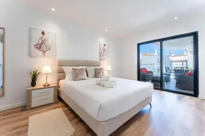 a white bedroom with a large bed and a balcony at Stunning 3 BDR Flat W/ Rooftop Pool by LovelyStay in Albufeira
