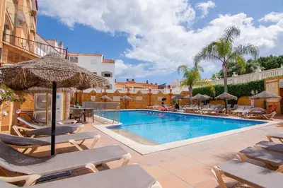 a swimming pool with chairs and umbrellas next to a building at Apartamento Turistico Silva in Albufeira