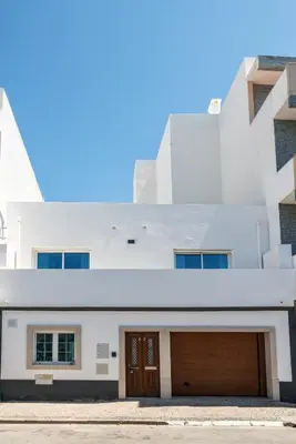 a white building with two garage doors in front of it at Privilege Casa dos Capuchinhos, in the heart of Faro in Faro