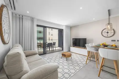 a living room with a couch and a dining room at Terracos de Quarteira II Navy by Real Properties in Quarteira