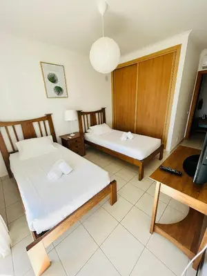 a room with two beds and a table and a tv at Ferreiras Villa in Albufeira