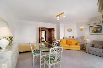 a living room with a table and a yellow couch at Vila Mar Azul in Quarteira