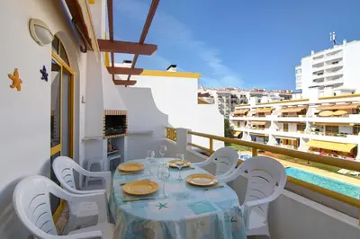 a table and chairs on a balcony with a pool at Vila Mar Azul in Quarteira