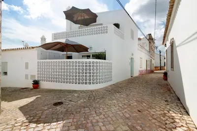 a white house with an umbrella on a cobblestone street at Casa de Benafim 51 in Benafim