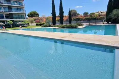 a large swimming pool with blue water in a building at Spacious Residence Golf apartment - Vilamoura in Quarteira
