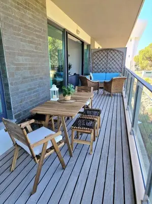 a wooden deck with a wooden table and chairs at Spacious Residence Golf apartment - Vilamoura in Quarteira