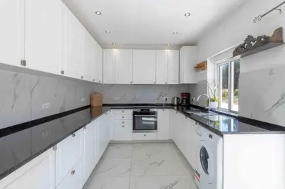 a white kitchen with white cabinets and a dishwasher at Casa Emella Luxury Villa Albufeira in Albufeira