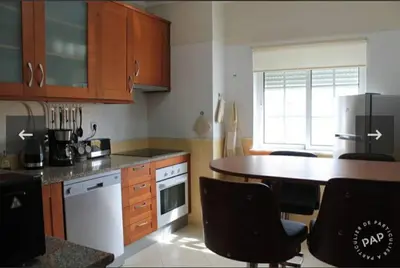 a kitchen with wooden cabinets and a table with chairs at Casa Mar à Vista in Cavacos