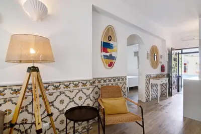 a living room with a chair and a surfboard on the wall at Blue wave escape apartment -T1 perto da praia com varanda in Albufeira