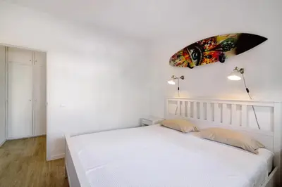 a bedroom with a white bed and a surfboard on the wall at Blue wave escape apartment -T1 perto da praia com varanda in Albufeira