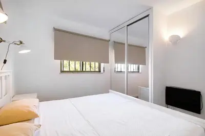 a white bedroom with a bed and a television at Blue wave escape apartment -T1 perto da praia com varanda in Albufeira