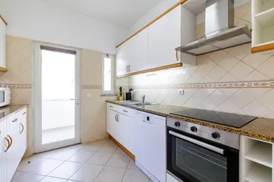a kitchen with white cabinets and a stove top oven at Sea-Front 1' Min! - Apartment with AC & WiFi in Quarteira