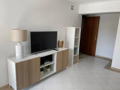 a living room with a television on a wooden entertainment center at Casa Porto Marina in Vilamoura