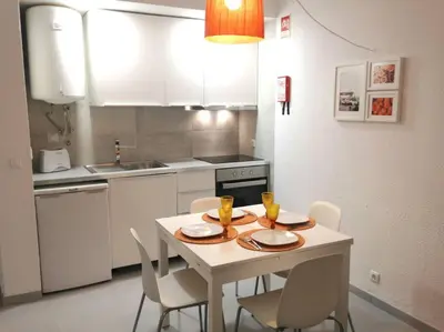 a kitchen with a white table and chairs and a kitchen with white cabinets at Casa Vila Magna T1 in Albufeira