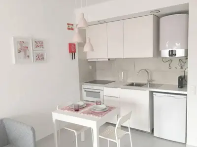 a white kitchen with a small table and chairs at CASA Vila Magna T0 in Albufeira