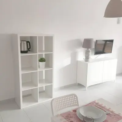a white living room with a table and a tv at CASA Vila Magna T0 in Albufeira