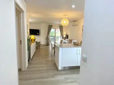a kitchen with white cabinets and a dining room at Albufeira Balaia Golf Vilage 3 With Pool by Homing in Albufeira