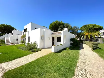 a white house with a palm tree in front of it at Albufeira Balaia Golf Vilage 3 With Pool by Homing in Albufeira
