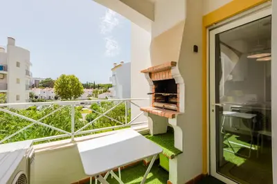 a balcony with a grill and a bench on a balcony at Alfamar Apartment at Praia da Falesia in Albufeira