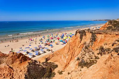 a beach with a crowd of people and umbrellas at Alfamar Apartment at Praia da Falesia in Albufeira