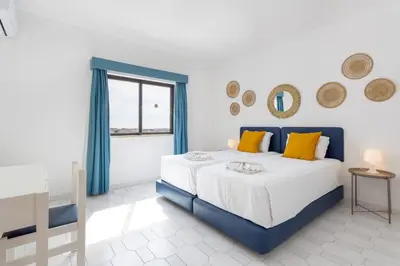 a bedroom with a bed with a yellow pillow and a mirror at #189 Montechoro Flat by Home Holidays in Albufeira