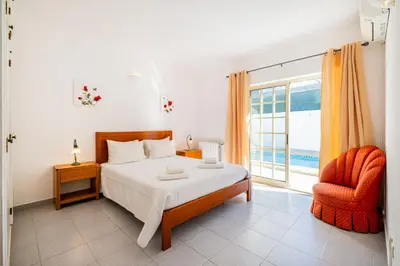 a bedroom with a bed and a chair and a window at Villa Nina in Albufeira