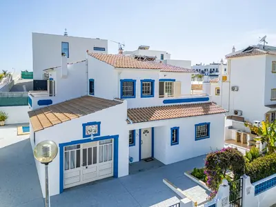 a white house with blue windows and a driveway at Villa Nina in Albufeira