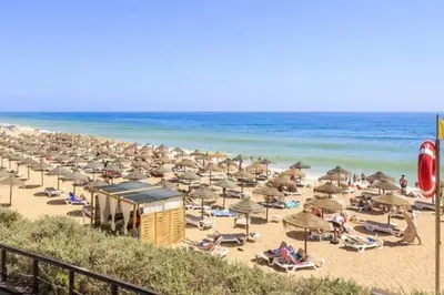 a beach with many chairs and umbrellas and the ocean at Vale do Lobo Algarve,Exclusive Private Pool Villa in Vale do Lobo