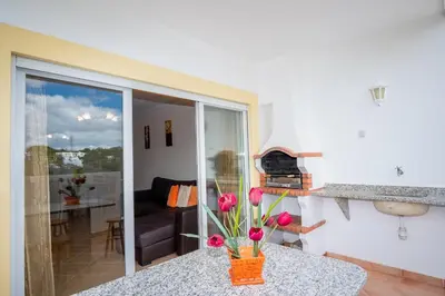 a room with a table with a vase with flowers on it at Thiago Holidays Apartment in Albufeira