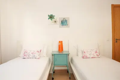 two beds with white sheets and an orange vase on a table at Villa Catarina Ocean View in Albufeira