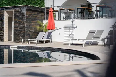a pool with two chairs and a red umbrella at Malpique heated pool & Jacuzzi Guest House in Albufeira