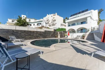 a patio with a pool and chairs and a building at Malpique heated pool & Jacuzzi Guest House in Albufeira
