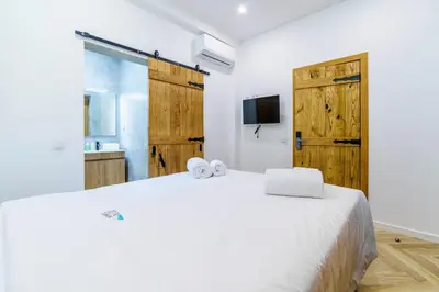 a bedroom with a white bed and wooden doors at Atlantic Bliss in Albufeira