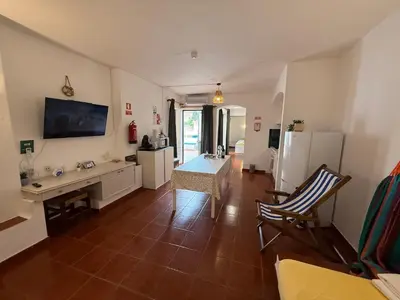 a living room with a table and a refrigerator at Casa da Oura in Albufeira