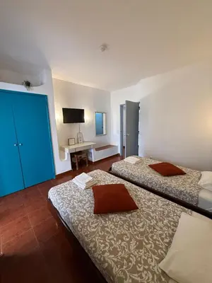 a bedroom with two beds and a desk with a television at Casa da Oura in Albufeira