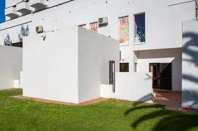 a white building with green grass in front of it at Casa da Oura in Albufeira