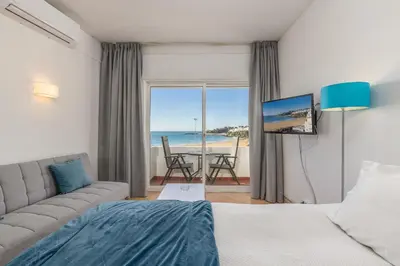 a bedroom with a bed and a view of the ocean at Apartamentos Pescadores in Albufeira