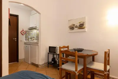a dining room with a table and chairs and a kitchen at Apartamentos Pescadores in Albufeira