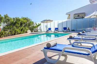 a swimming pool with lounge chairs and umbrellas at Villa Namora in Albufeira