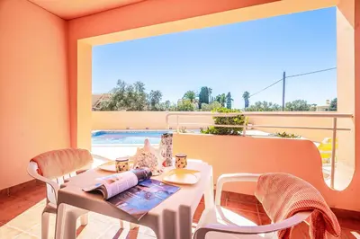 a white table and chairs on a balcony with a pool at Casa Pluma in Albufeira