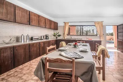 a kitchen with a long table with chairs and a kitchen with at Casa Pluma in Albufeira