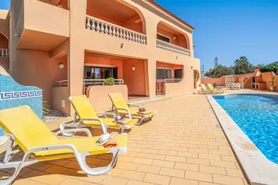 a group of yellow lounge chairs next to a swimming pool at Casa Pluma in Albufeira