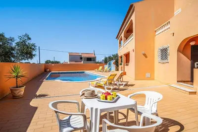 a patio with a table and chairs and a pool at Casa Pluma in Albufeira