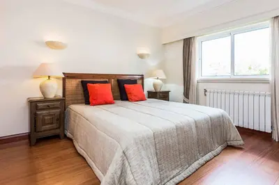 a bedroom with a large bed with two orange pillows at Villa Luz Figueiras in Galé