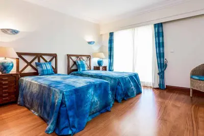 two beds in a bedroom with blue sheets at Villa Luz Figueiras in Galé