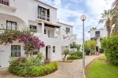 a white building with purple flowers and a street light at Seaside Retreat with Pool, AC, and Fast Wi-Fi in Albufeira