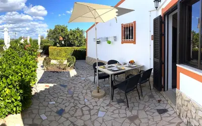 a patio with a table and an umbrella at Casa da Horta, Vale carro Olhos de Agua in Albufeira