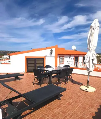 a patio with a table and chairs and an umbrella at Casa da Horta, Vale carro Olhos de Agua in Albufeira