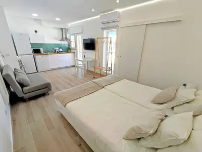 a bedroom with a large bed and a kitchen at Lovely Terrace Studio Baixa Faro in Faro